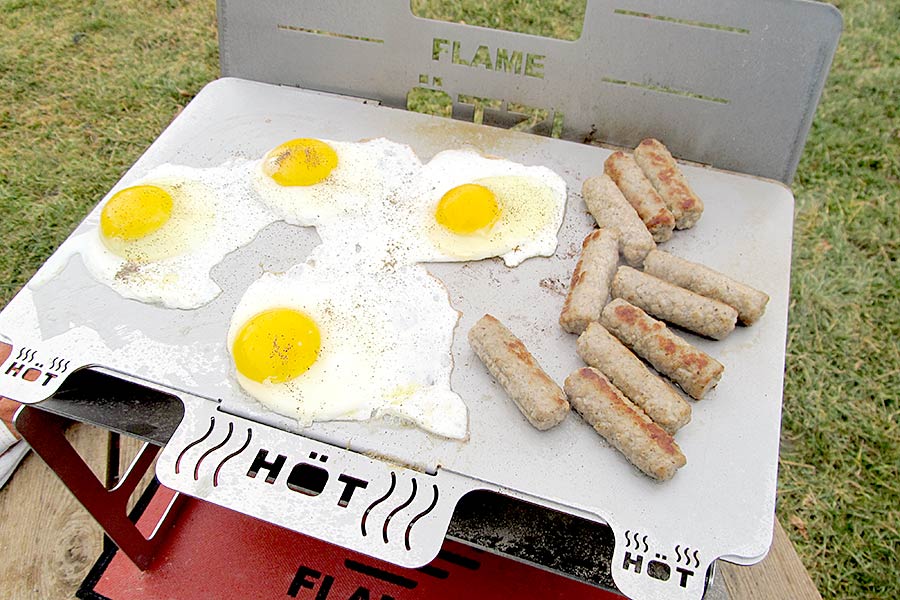 Cooking eggs and sausage on portable grill
