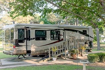 RV parked under trees at campground