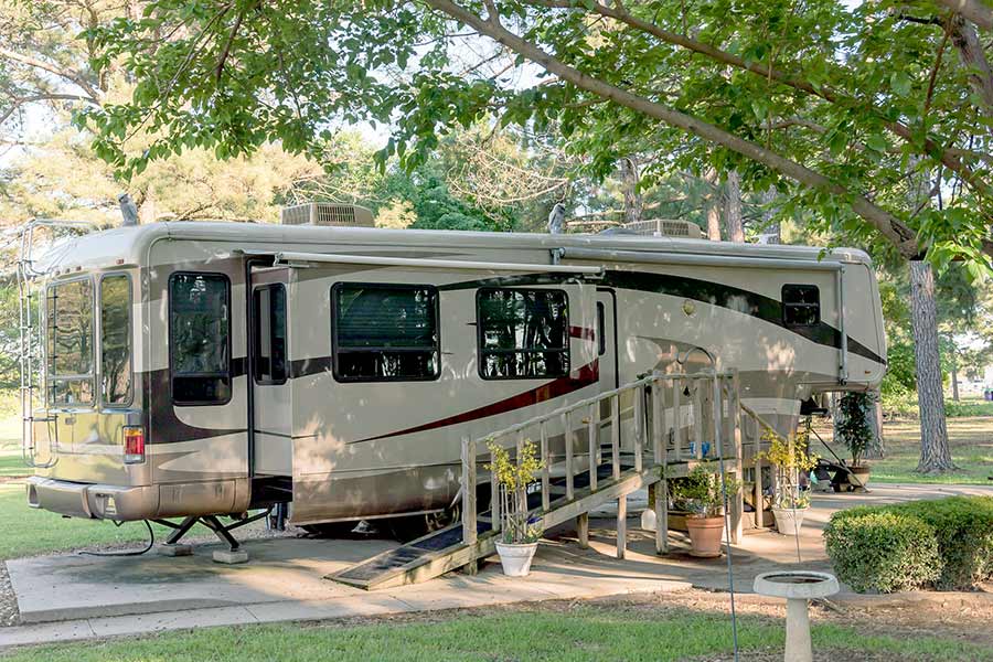 Fifth wheel RV parked under trees at campground