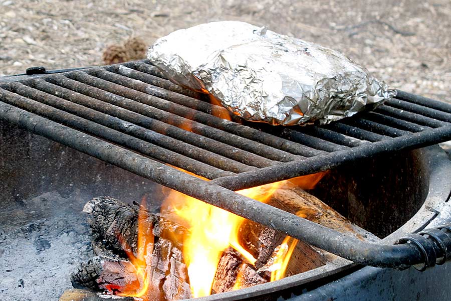 Dinner in foil packet cooking over campfire