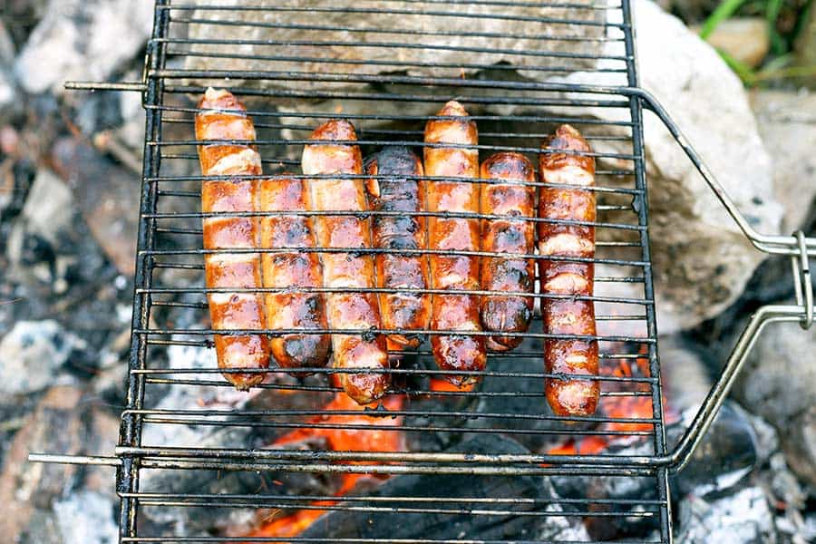 Cooking hotdogs in wire basket over campfire