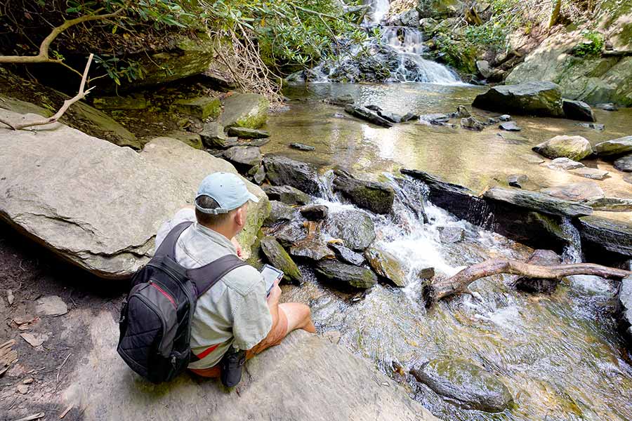 Hiker sitting beside a small stream in the forest