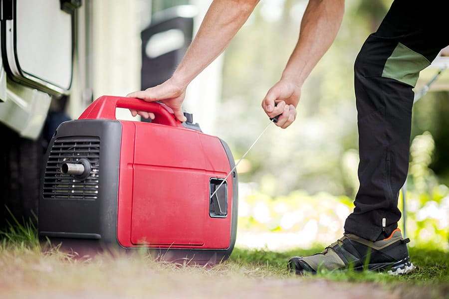 Man at campground starting a red generator