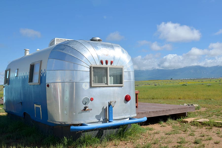 Old Airstream travel trailer sitting in a scenic valley