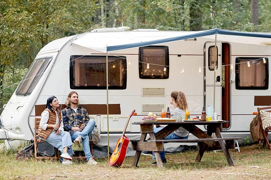 Family sitting in front of travel trailer during camping trip