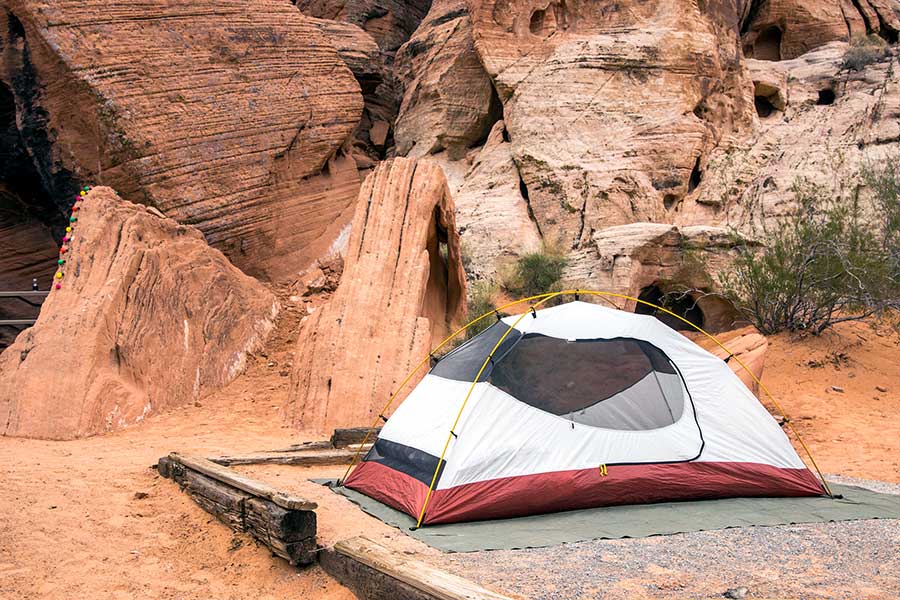 Red and white tent at a campsite among red sandstone rocks